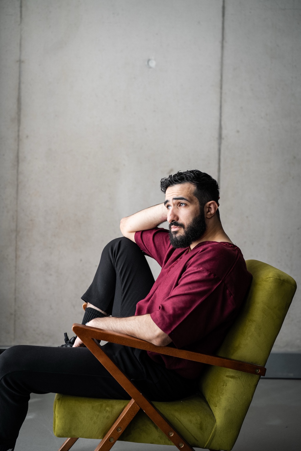 Mohamed Chahrour: Seated sideways in a green chair, wearing burgundy