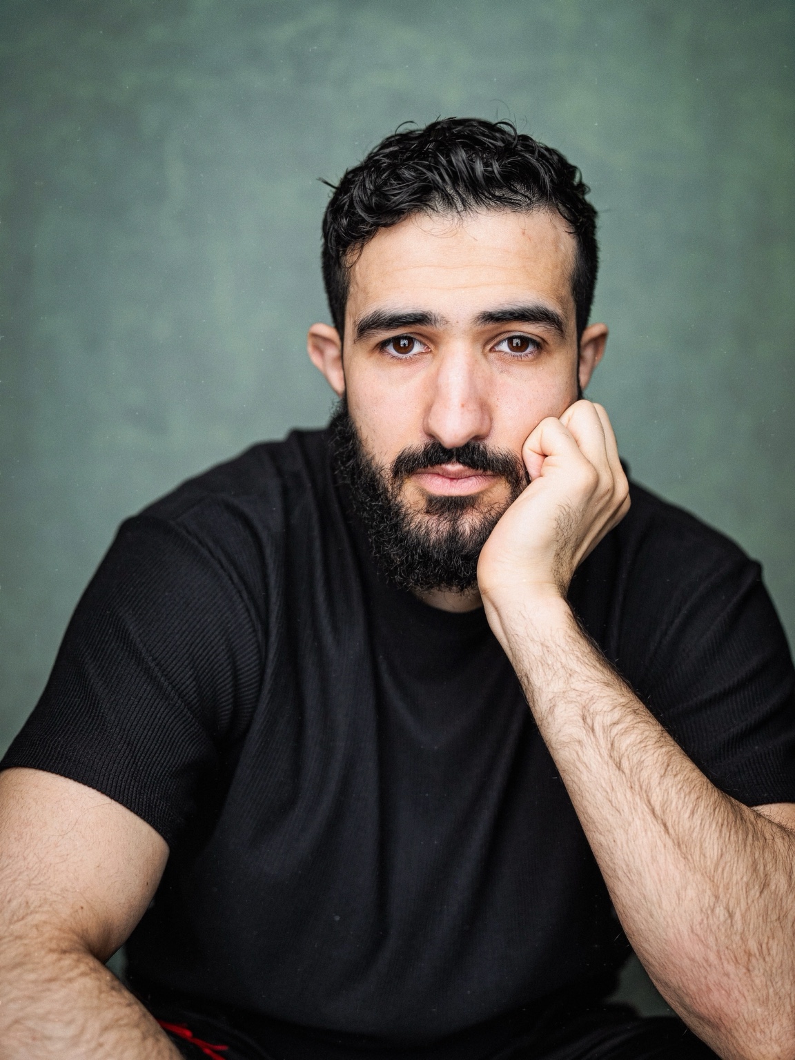 Mohamed Chahrour: Portrait in a black shirt, resting his head on his hand